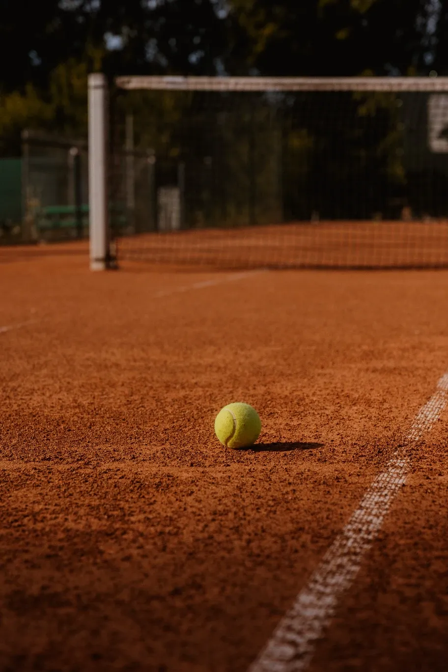 Tennisball auf einem Sandplatz vor dem Netz